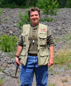 Prof. Nathalie Brandes working in the field, holding a mining rock pick.